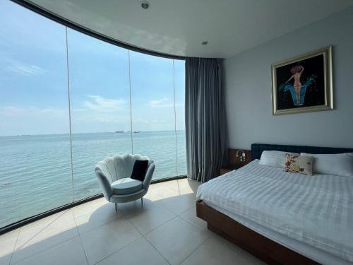 a bedroom with a bed and a chair and a large window at Nancy Tran Grand Strip Sweet Villa 1 in Vung Tau