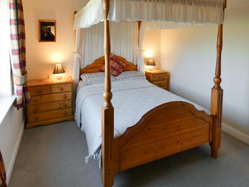 a bedroom with a wooden bed and two night stands at Bournstream Cottage in Withycombe