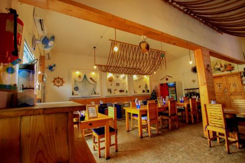 un restaurant avec des tables et des chaises en bois et un lustre dans l'établissement Hotel Le Prince, à Cotonou