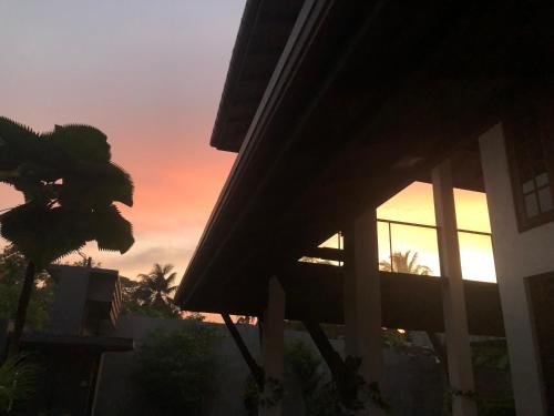 a sunset seen from a house with a palm tree at Sunshine Holiday Home at Wattala in Wattala