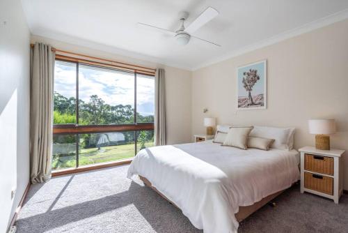 a white bedroom with a bed and a large window at Laguna Niguel - Acreage in Tuggerah