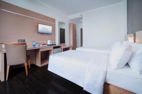 a hotel room with a bed and a desk at Noola Hotel Cilacap in Gumilir