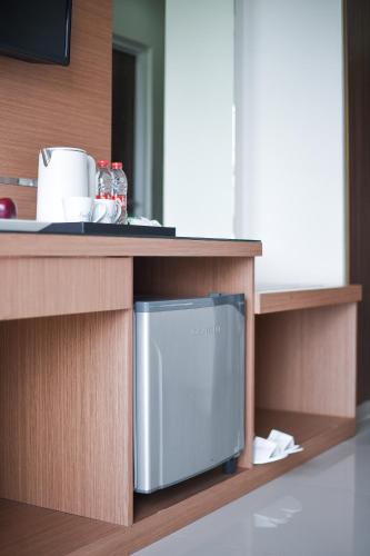a microwave on a shelf in a kitchen at Noola Hotel Cilacap in Gumilir