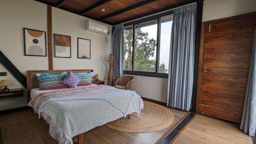 een slaapkamer met een bed en een groot raam bij The Pipal Tree, Mountain Villa in Pokhara, Methlang in Pokhara