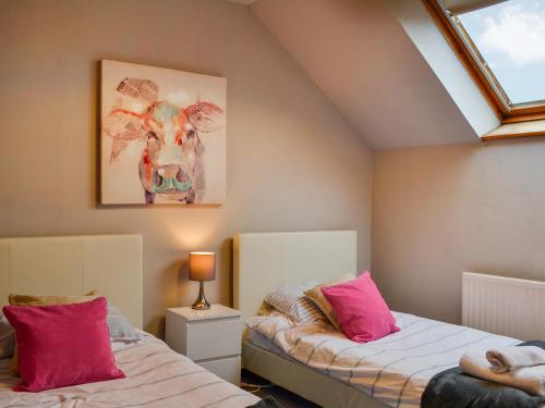 a attic bedroom with two beds with pink pillows at Airdside Cottage in Crossmichael