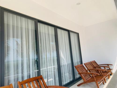 three chairs sitting on a balcony with windows at Bờ Biển Vàng Resort in Ke Ga