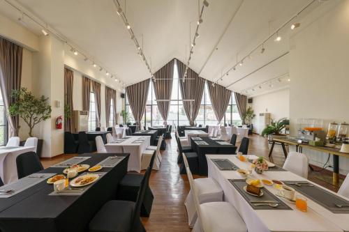 a dining room with black tables and white chairs at Eight Hotel Ari in Bangkok