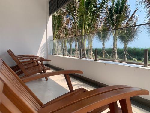a balcony with three chairs and a window with palm trees at Bờ Biển Vàng Resort in Ke Ga