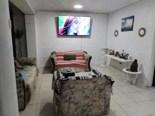 un soggiorno con divani e TV a parete di Dpto. 1er piso 4 hab.Piscina Terraza a Punta Hermosa