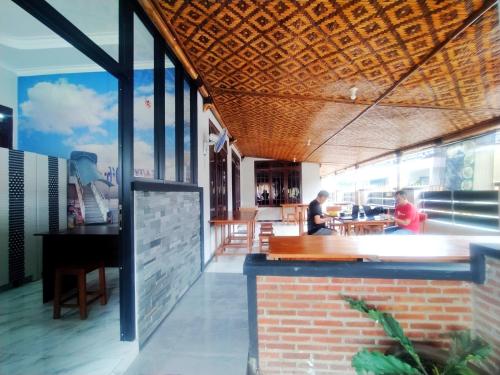 a restaurant with a bar and people sitting at tables at RedDoorz Syariah Near Stasiun Purwokerto in Purwokerto