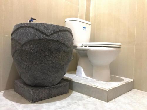 a toilet in a bathroom with a statue next to it at Grand Hagawa Syariah near Alun Alun Lamongan RedPartner in Lamongan