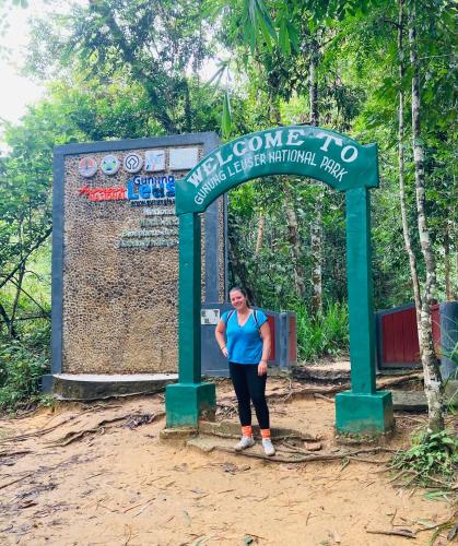 a woman standing in front of a sign at a park at Leuser Inn in Bukit Lawang