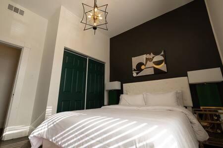 a bedroom with a large white bed with a green door at Knox Vegas in Knoxville