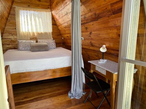 フォルトゥナにあるTiny Villa Experienceのベッドと机が備わった丸太小屋の寝室