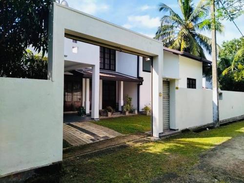 een wit huis met een binnenplaats en palmbomen bij Colombo Villa Near Bolgoda Lake 5 Bed 2.5 Bath in Piliyandala
