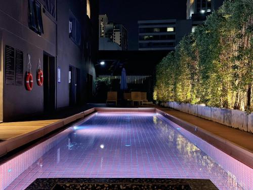 a swimming pool with purple lights in a building at Eight Hotel Ari in Bangkok