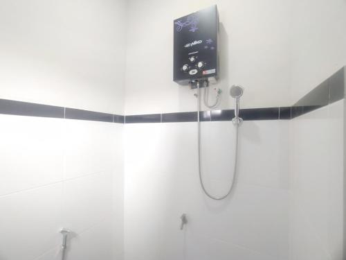 ein Bad mit einer Dusche und einem TV an der Wand in der Unterkunft RedDoorz Syariah Near Stasiun Purwokerto in Purwokerto