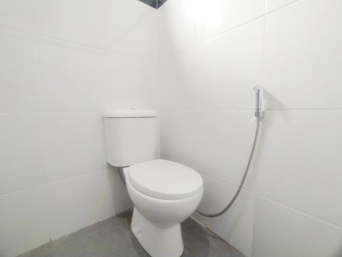 a bathroom with a white toilet with a hose at RedDoorz Syariah Near Stasiun Purwokerto in Purwokerto