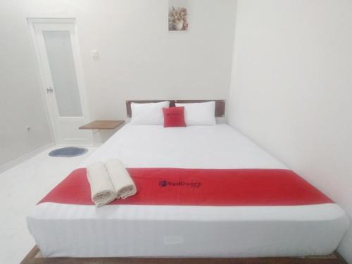 a large white bed with a red blanket on it at RedDoorz Syariah Near Stasiun Purwokerto in Purwokerto
