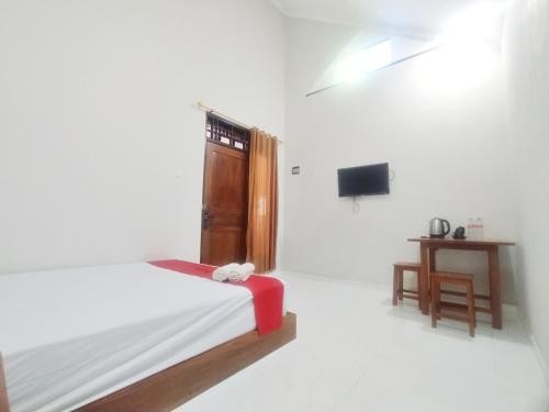 a white room with a bed and a table at RedDoorz Syariah Near Stasiun Purwokerto in Purwokerto