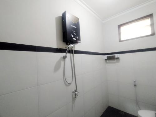 a bathroom with a shower with a tv on the wall at RedDoorz Syariah Near Stasiun Purwokerto in Purwokerto