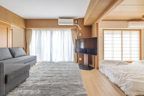 a living room with a couch and a flat screen tv at A Marvelous Blend of Tradition and Modernity, Independent 1st-floor Suite, Accommodates Up to 10 Guests! in Tokyo