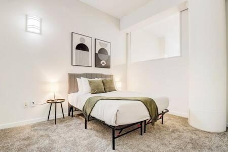 a white bedroom with a bed and a table at CozySuites - 2BR with Direct Skybridge Access #5 in Indianapolis