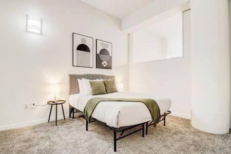 a white bedroom with a bed and a table at CozySuites - 2BR with Direct Skybridge Access #7 in Indianapolis
