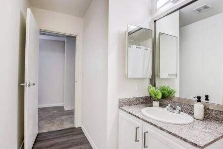 a white bathroom with a sink and a mirror at CozySuites - 2BR with Direct Skybridge Access #10 in Indianapolis