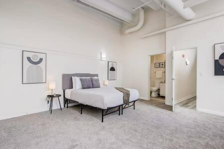 ein Schlafzimmer mit einem Bett in einem weißen Zimmer in der Unterkunft CozySuites 2BR - 2BA with Skybridge Access #1 in Indianapolis