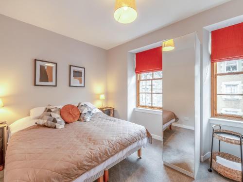 sypialnia z łóżkiem z czerwonymi zasłonami i lustrem w obiekcie Castlegate w mieście Jedburgh