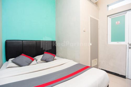 Tempat tidur dalam kamar di J&B Rooms Utan Kayu Jakarta Mitra RedDoorz