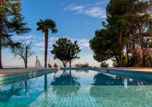 a swimming pool with a palm tree in the background at La Botigueta de Bellmunt in Penellas