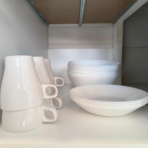 a group of white bowls and plates on a shelf at Cozy & Drive Urban Suite by WL in Jelutong