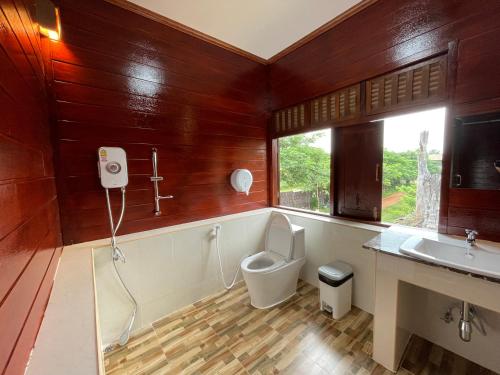 a bathroom with a toilet and a sink and a window at อีสานบ้านเฮาฟาร์ม Esan Banhao Farm in Ban Om Ko
