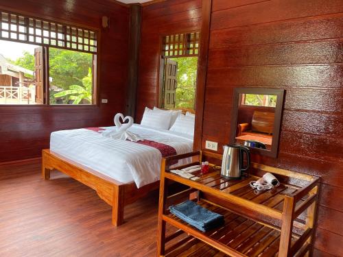 a bedroom with a bed and a table with a mirror at อีสานบ้านเฮาฟาร์ม Esan Banhao Farm in Ban Om Ko