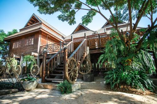 a house with large wooden wheels in front of it at อีสานบ้านเฮาฟาร์ม Esan Banhao Farm in Ban Om Ko