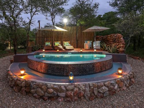 a swimming pool with lights in a yard at Grace of Africa, Couples 5 STAR Nature Lodge in Marloth Park
