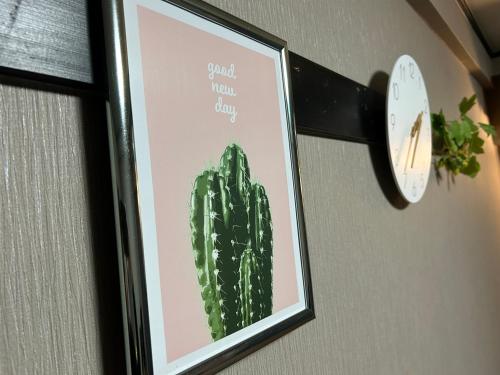 uma imagem de um cacto numa parede com um relógio em Guest House GENESIS OF FREEDOM INN em Fukuoka