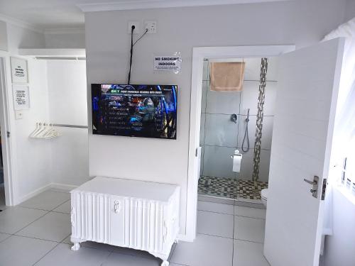 a bathroom with a shower and a television on the wall at Close to the sea - Upstairs Sea Facing En Suite Bedroom In Main House in Durban