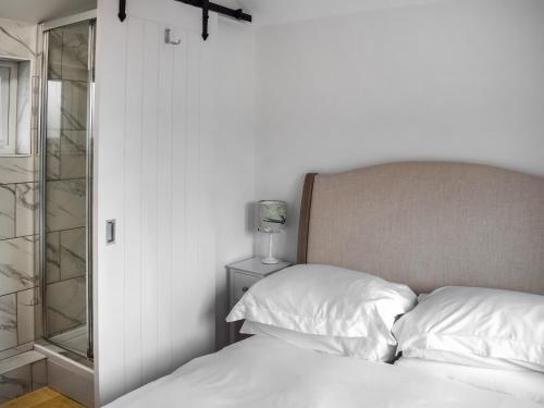 um quarto com uma cama com lençóis brancos e um espelho em Cripps Cottage Annex em Hassocks