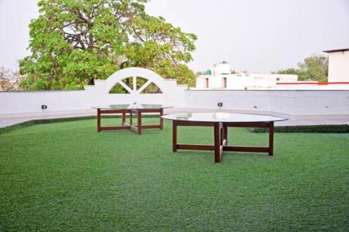 two tables on a green field with a white wall at Mauji's Villa Hotel & Guest House in Prayagraj
