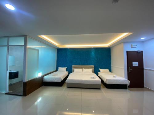 two beds in a room with blue walls at Codidik Hotel in Kuantan
