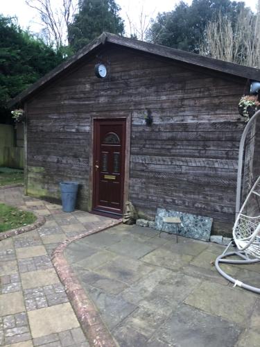 a wooden building with a door and a patio at The Barn in Trotterscliffe
