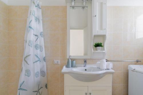 La salle de bains est pourvue d'un lavabo et d'un rideau de douche. dans l'établissement Terrazza vista mare e box auto, à Gallipoli