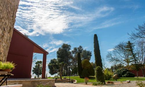 a view of a garden with trees and a cloudy sky at La Botigueta de Bellmunt in Penellas