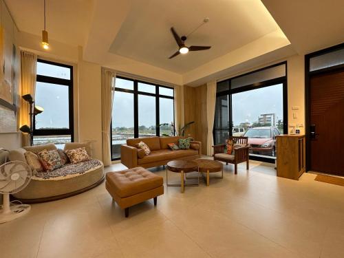 a living room with a couch and chairs and windows at 全新根本家民宿 寵物友善 電動麻將 兒童遊戲區 廚房 in Sanxing