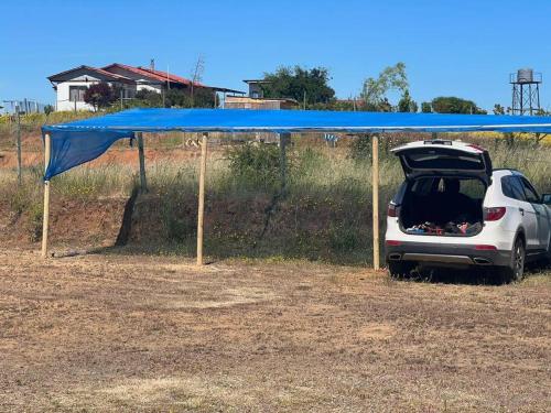 a car parked under a blue canopy in a field at Casa los cabreras in Quillón