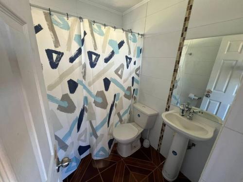 a bathroom with a toilet and a sink and a shower curtain at Casa los cabreras in Quillón