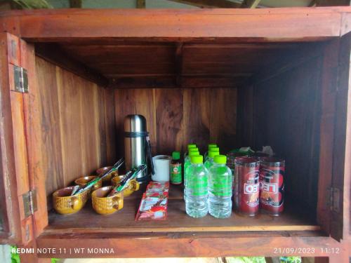 une étagère en bois avec des bouteilles d'eau et d'autres articles dans l'établissement ม่อนนาป่าบงเปียง โฮมสเตย์, à Ban Mae Pan Noi